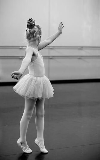 Djevojčica balerina raširenih ruku u pokretu. 
