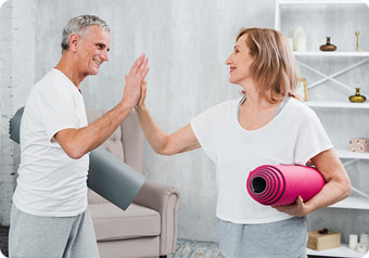 Dvoje starijih ljudi s prostirkama za vježbanje si daje ruku nakon vježbanja. 