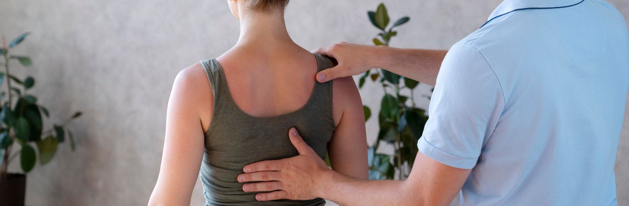 fizioterapeut drži dlan na leđima pacijentice i vodi ju kroz vježbe za kifozu