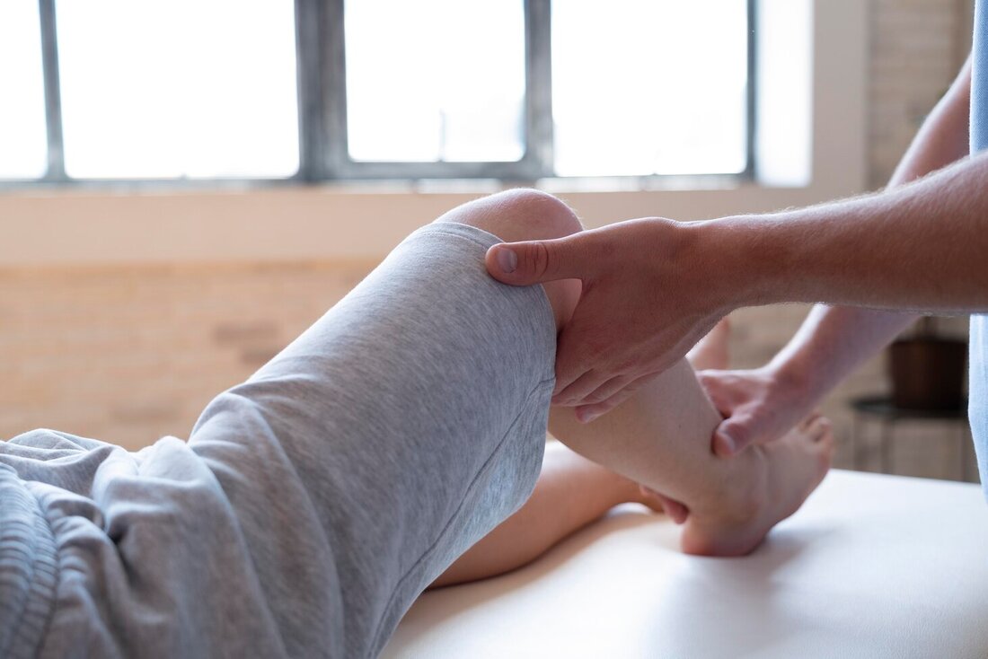 Fizioterapeut rukama dodiruje koljeno pacijenta koji leži na stolu. 