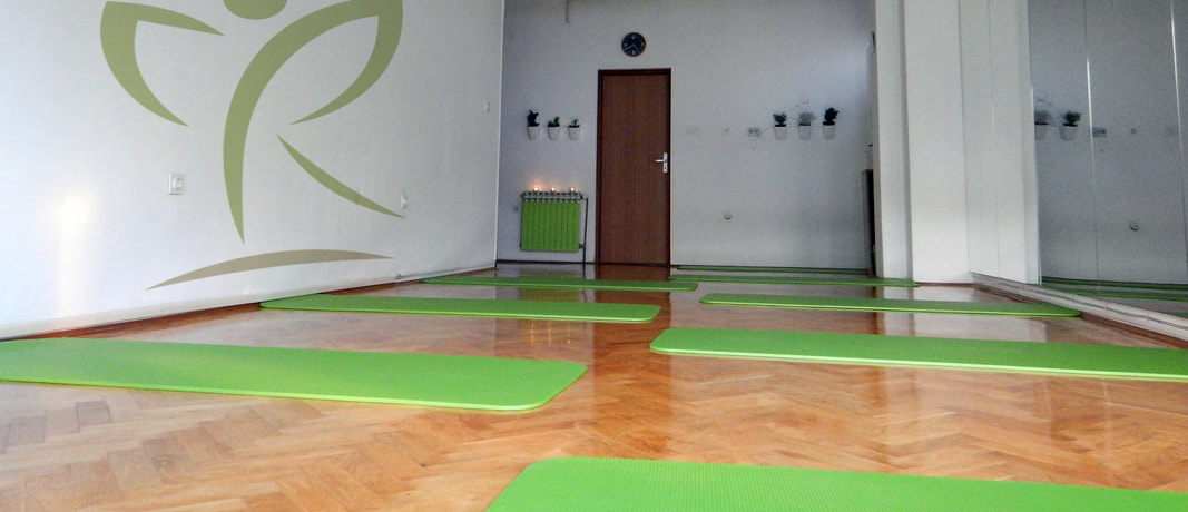 Dvorana za vježbanje s velikim ogledalima i zelenim prostirkama na drvenom podu. 
