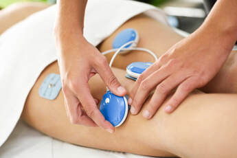 fizioterapeut rukama postavlja elektrode na tijelo pacijenta za elektro stimulaciju u liječenju išijasa