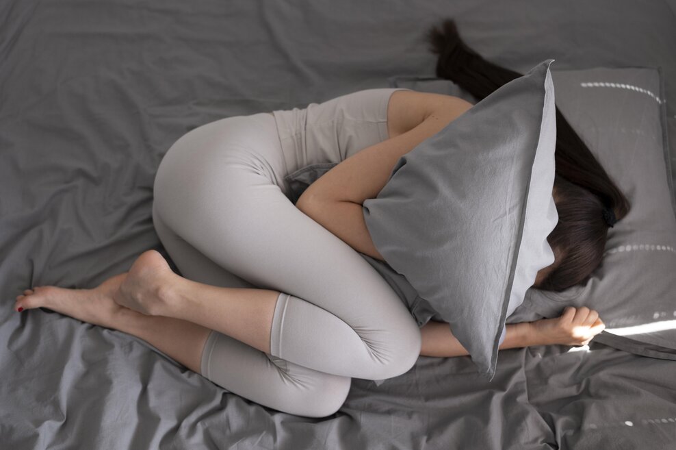 Mlada žena leži sklupčana i grli jastuk